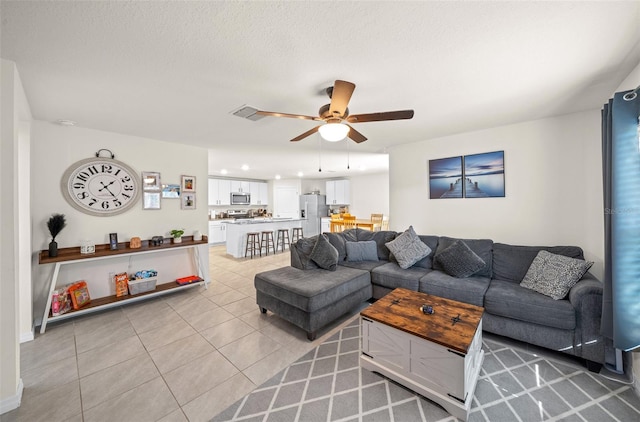 tiled living room with ceiling fan and a textured ceiling