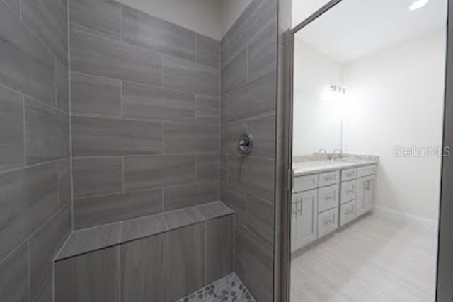 bathroom featuring a tile shower and vanity