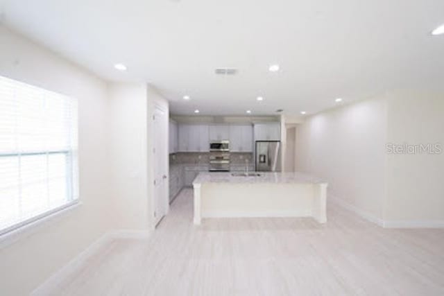 kitchen featuring recessed lighting, stainless steel fridge with ice dispenser, light countertops, baseboards, and white microwave