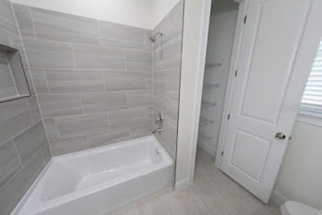 bathroom with toilet and tiled shower / bath