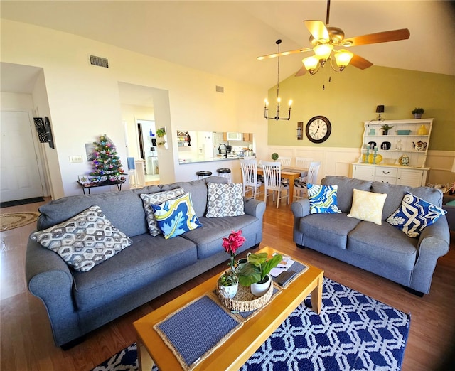 living room featuring vaulted ceiling, sink, dark hardwood / wood-style floors, and ceiling fan with notable chandelier