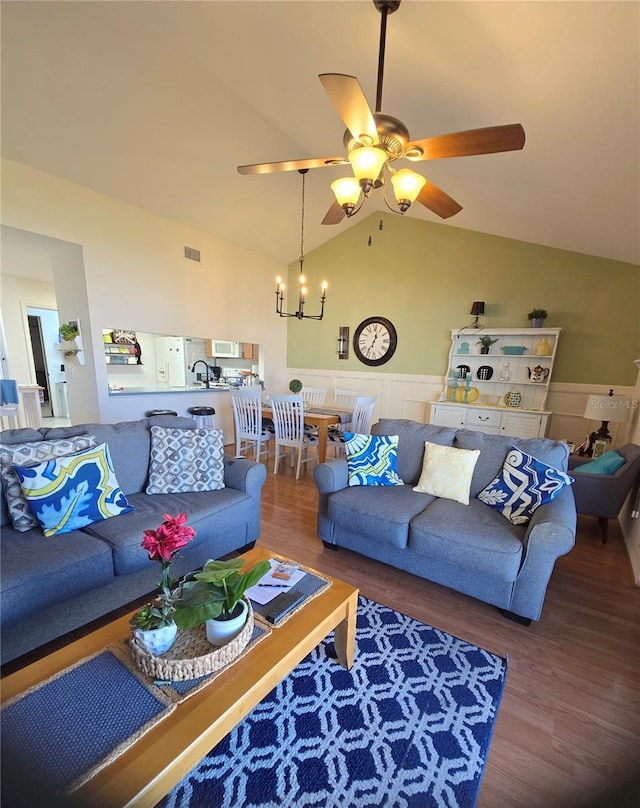 living room with ceiling fan with notable chandelier, wood-type flooring, and lofted ceiling