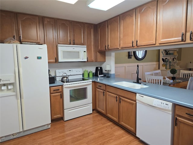 kitchen with light wood-type flooring, white appliances, and sink