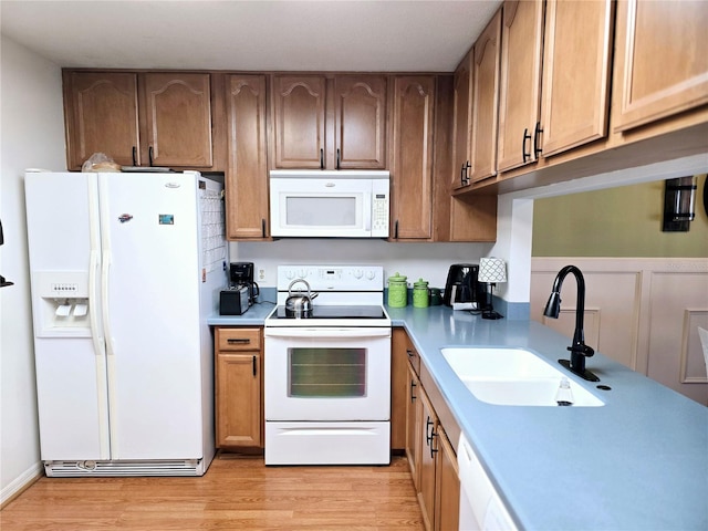 kitchen featuring light hardwood / wood-style floors, white appliances, and sink