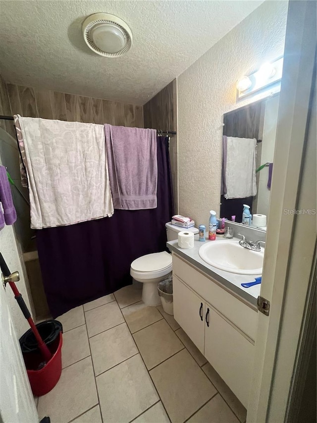 bathroom with a textured ceiling, tile patterned flooring, vanity, and toilet