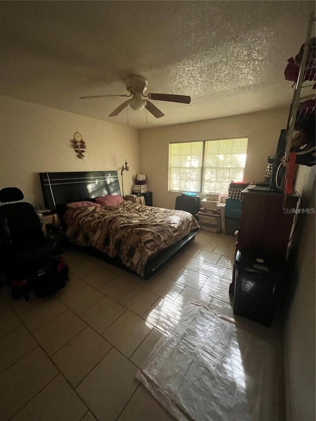 tiled bedroom with a textured ceiling and ceiling fan