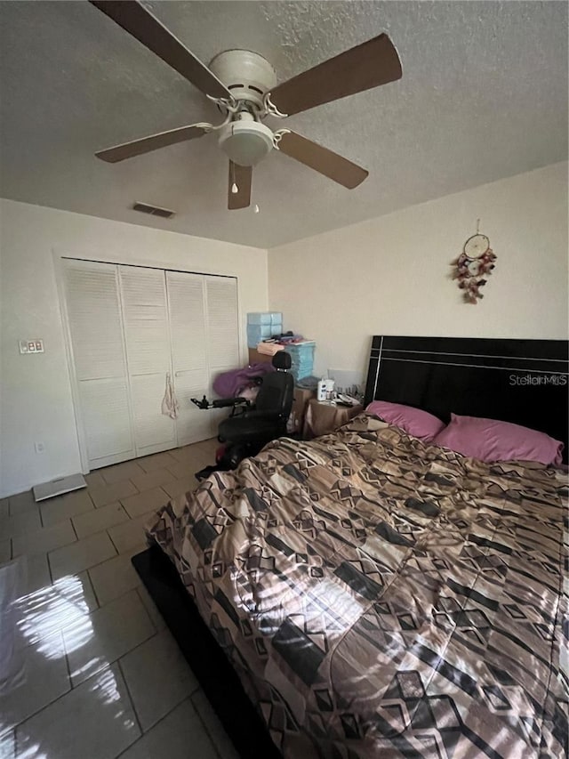 tiled bedroom featuring a textured ceiling, ceiling fan, and a closet