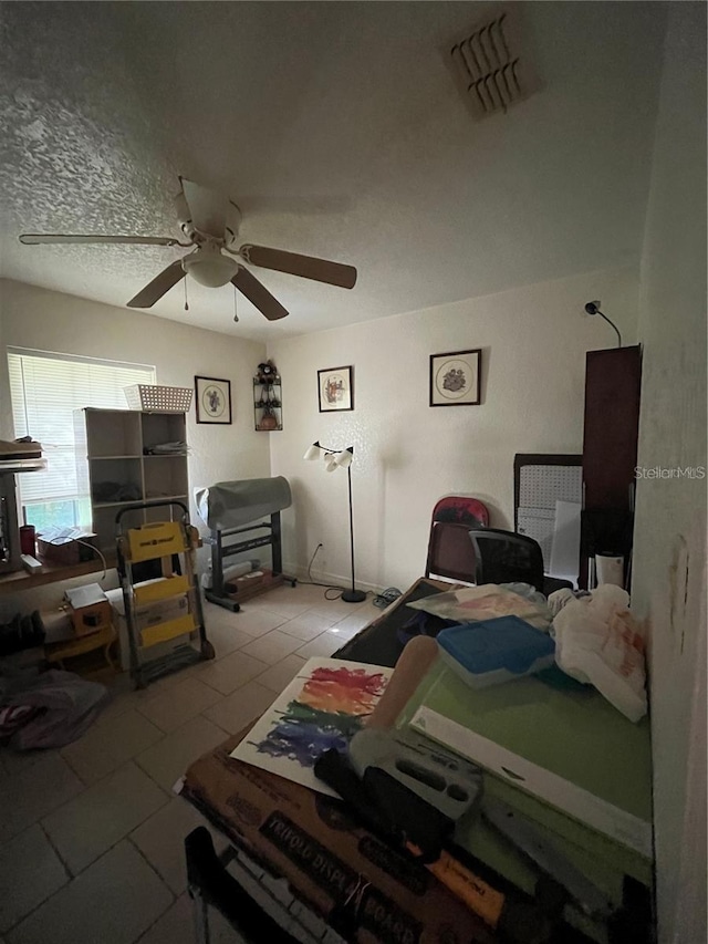 bedroom featuring ceiling fan, tile patterned flooring, and a textured ceiling