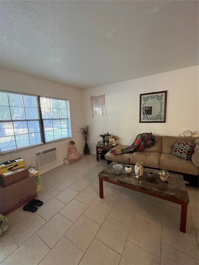 living room featuring a wall unit AC, a textured ceiling, and light tile patterned floors