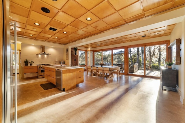 kitchen featuring appliances with stainless steel finishes, a center island with sink, and wall chimney exhaust hood