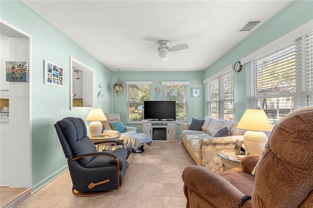 tiled living room featuring ceiling fan and wooden walls