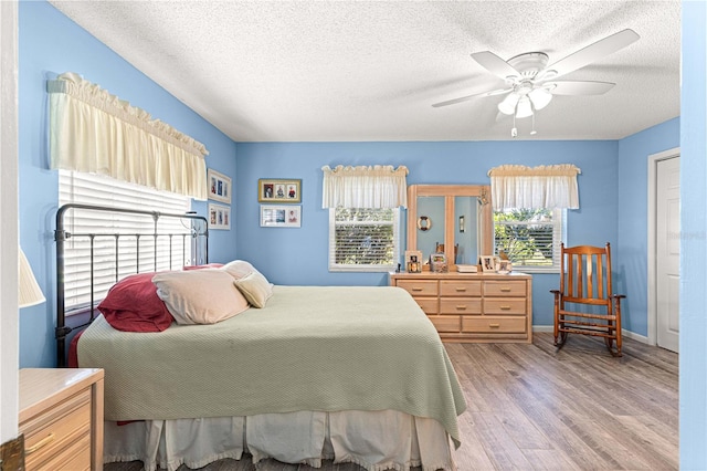 bedroom with ceiling fan, a textured ceiling, and light wood-type flooring