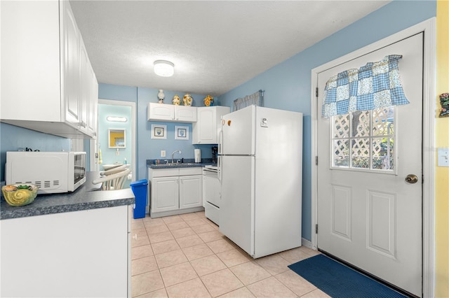 kitchen with white cabinets, white appliances, a textured ceiling, and light tile patterned floors