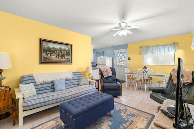 living room with ceiling fan, light tile patterned floors, and a textured ceiling