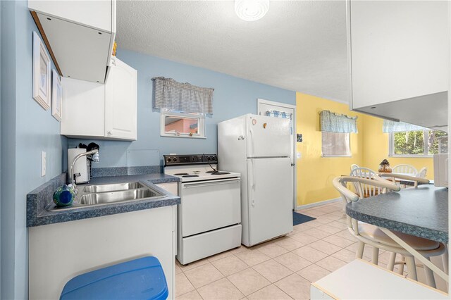 kitchen featuring a textured ceiling, white appliances, sink, light tile patterned floors, and white cabinetry