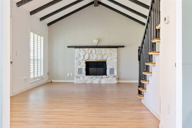 unfurnished living room featuring a fireplace, beam ceiling, high vaulted ceiling, and light hardwood / wood-style flooring