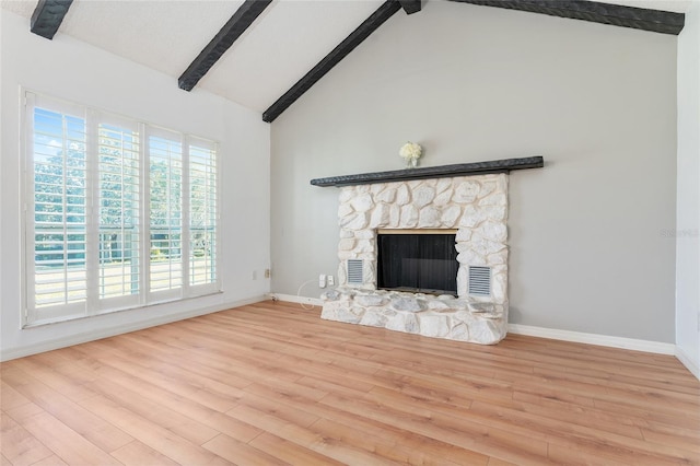 unfurnished living room featuring a fireplace, high vaulted ceiling, light hardwood / wood-style flooring, and beamed ceiling