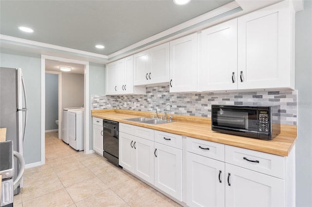 kitchen with wood counters, black appliances, white cabinets, sink, and washing machine and dryer