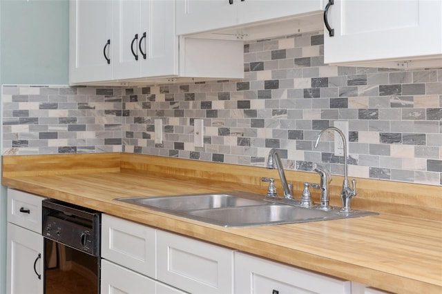 kitchen with white cabinets, black dishwasher, backsplash, and wooden counters