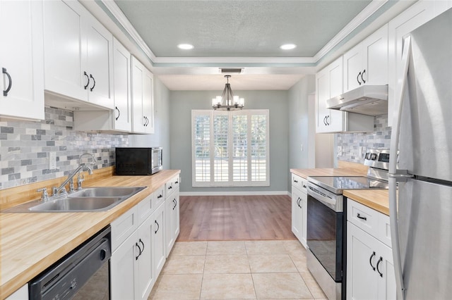 kitchen with butcher block counters, hanging light fixtures, white cabinets, and stainless steel appliances