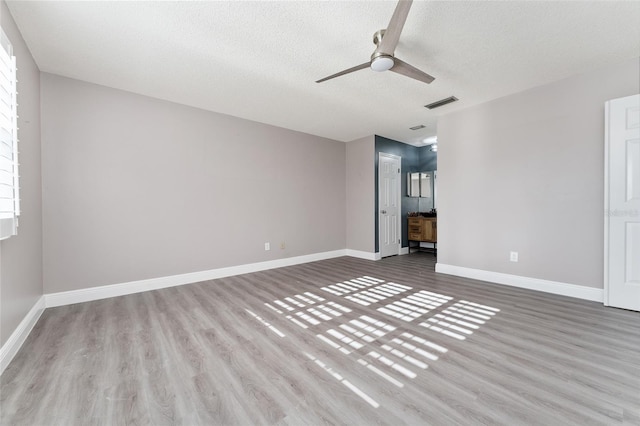 spare room with a textured ceiling, light wood-type flooring, and ceiling fan