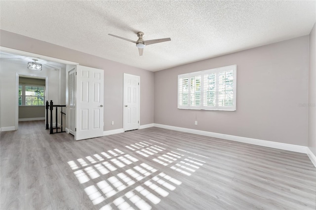 unfurnished room featuring a textured ceiling, light wood-type flooring, and ceiling fan