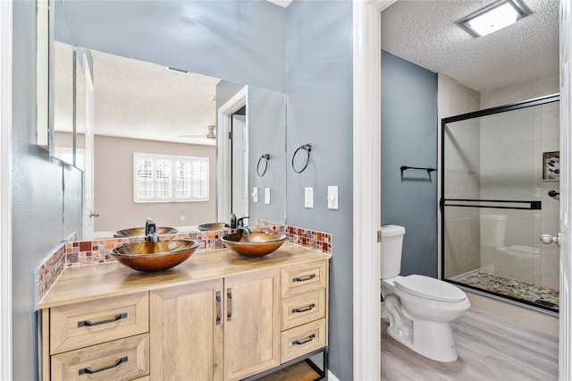 bathroom featuring a textured ceiling, toilet, vanity, a shower with shower door, and hardwood / wood-style flooring