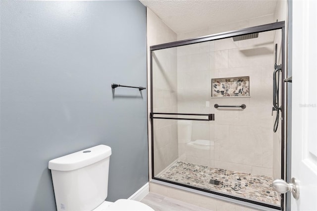 bathroom with a shower with shower door, a textured ceiling, and toilet