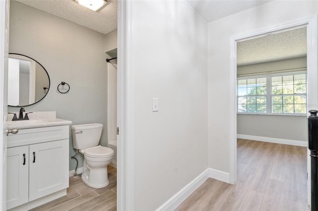 full bathroom with hardwood / wood-style floors, vanity,  shower combination, toilet, and a textured ceiling