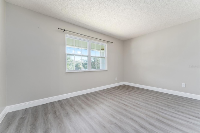 spare room featuring light wood-type flooring and a textured ceiling