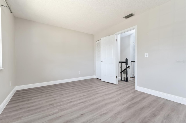 unfurnished room with light hardwood / wood-style flooring and a textured ceiling