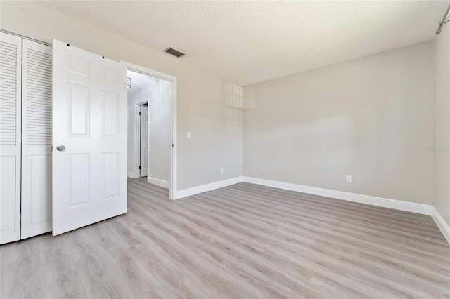 unfurnished bedroom with light wood-type flooring, a textured ceiling, and a closet