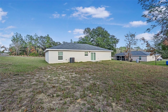 rear view of property with a yard and central air condition unit