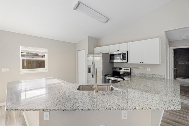 kitchen featuring light stone countertops, white cabinetry, stainless steel appliances, and lofted ceiling