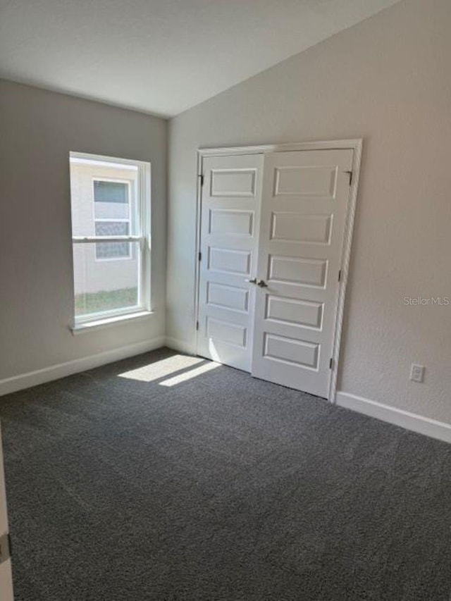 carpeted empty room with lofted ceiling and baseboards