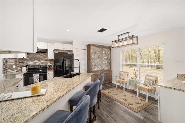 kitchen featuring light stone countertops, dark hardwood / wood-style floors, black appliances, white cabinetry, and sink