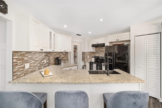 kitchen with black appliances, tasteful backsplash, white cabinets, and kitchen peninsula