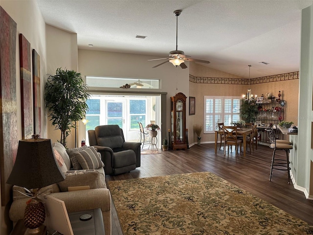 living room with vaulted ceiling, a textured ceiling, dark wood-type flooring, and ceiling fan with notable chandelier