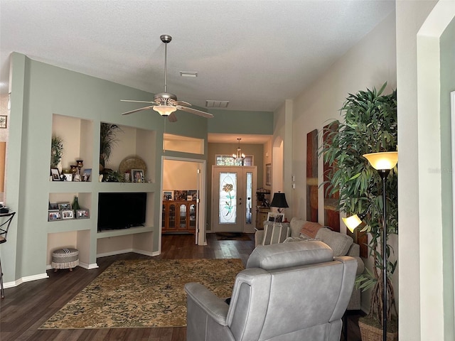 living room featuring ceiling fan with notable chandelier, built in shelves, dark hardwood / wood-style flooring, and a textured ceiling