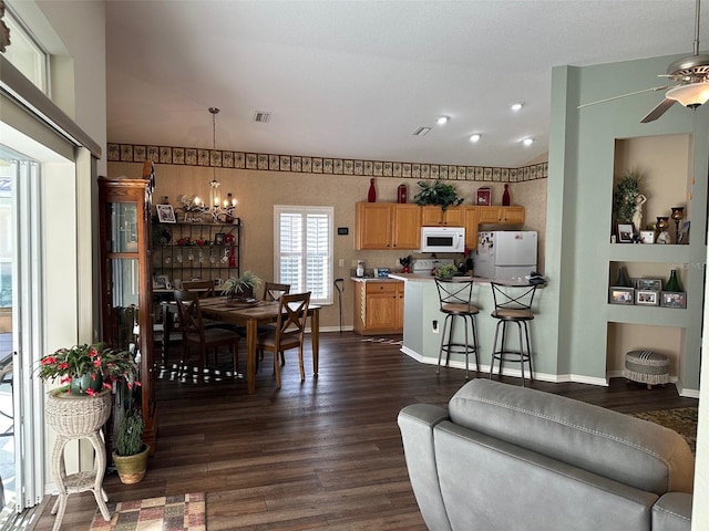 living room with ceiling fan with notable chandelier and dark hardwood / wood-style floors