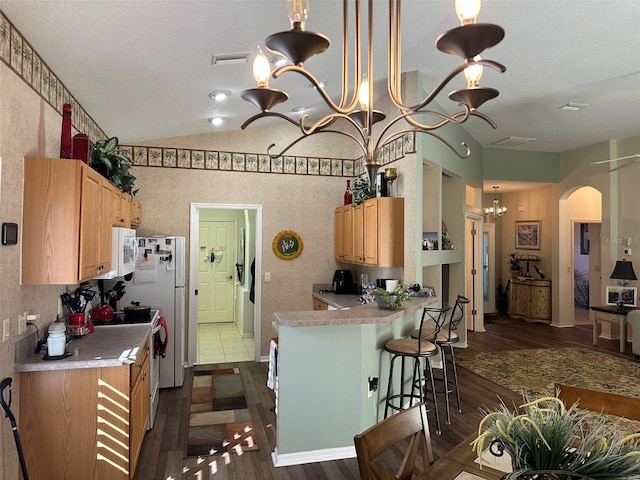 kitchen featuring white appliances, dark wood-type flooring, pendant lighting, a notable chandelier, and a breakfast bar area