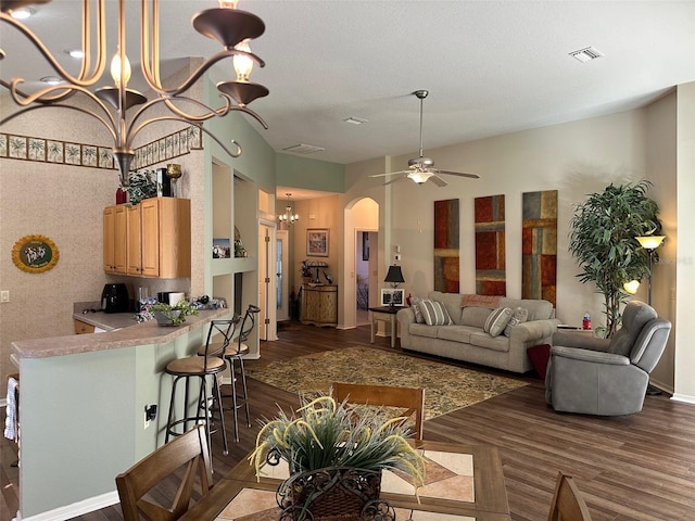 living room with ceiling fan with notable chandelier and dark hardwood / wood-style floors