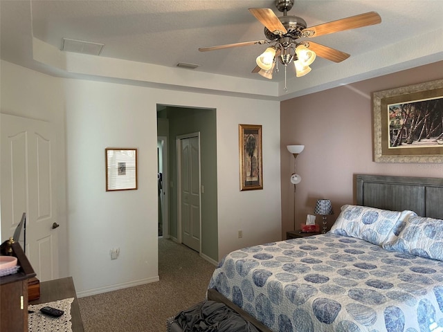 carpeted bedroom featuring ceiling fan and a raised ceiling