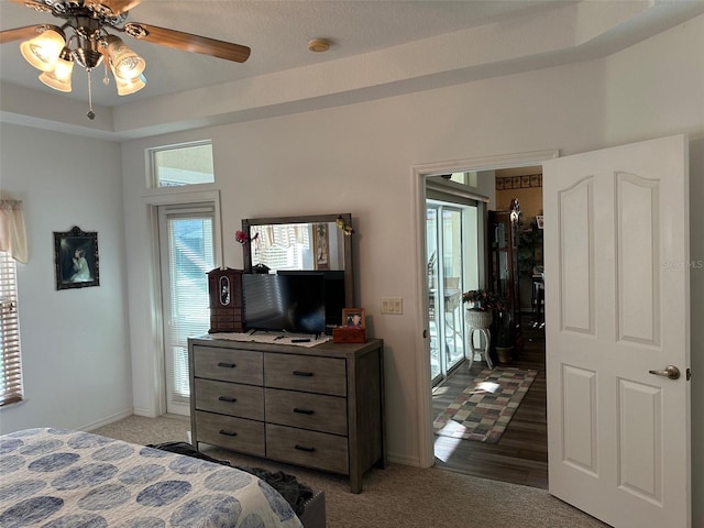 carpeted bedroom with ceiling fan and a raised ceiling