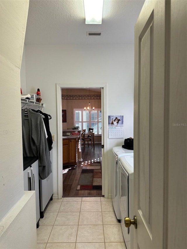 laundry room with washer and clothes dryer, light tile patterned floors, a chandelier, and a textured ceiling