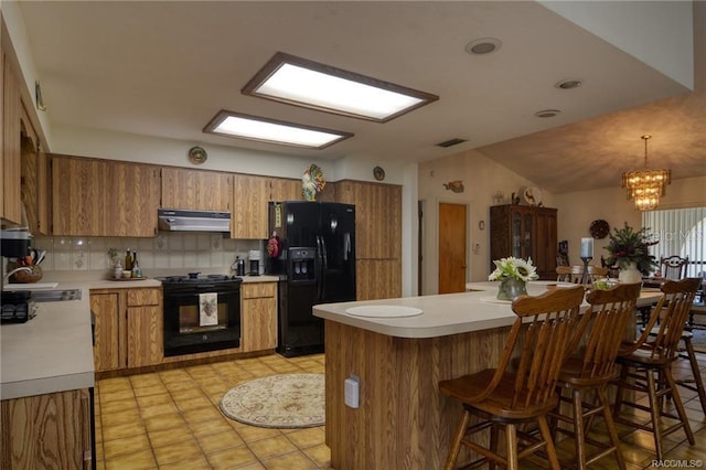 kitchen featuring tasteful backsplash, sink, black appliances, decorative light fixtures, and a notable chandelier