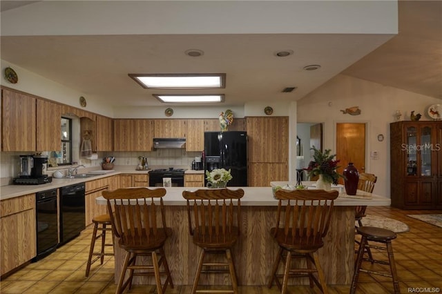 kitchen with black appliances, a kitchen breakfast bar, and tasteful backsplash