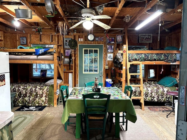 dining space featuring ceiling fan and wooden walls