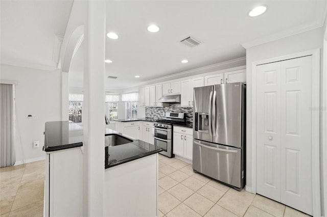 kitchen featuring backsplash, kitchen peninsula, white cabinetry, appliances with stainless steel finishes, and light tile patterned floors