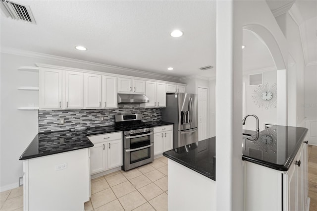 kitchen with light tile patterned floors, an island with sink, appliances with stainless steel finishes, tasteful backsplash, and white cabinets